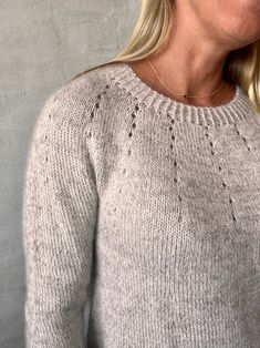 a blonde woman wearing a gray sweater and glasses