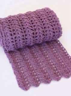 a purple crocheted scarf laying on top of a white table