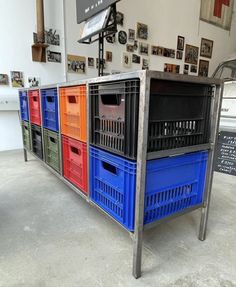 a bunch of crates sitting on top of a metal table in a room with pictures hanging on the wall