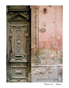 an old wooden door in front of a pink wall