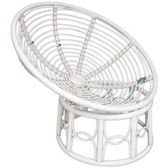 a white wicker chair with circular seat on it's back legs and arms