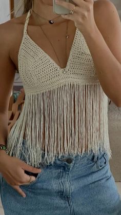 a woman taking a selfie with her cell phone while wearing a crochet top