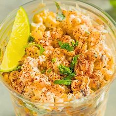 a glass bowl filled with macaroni salad and garnished with fresh herbs