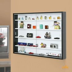 a wall mounted display case with various items on it and a television in the background