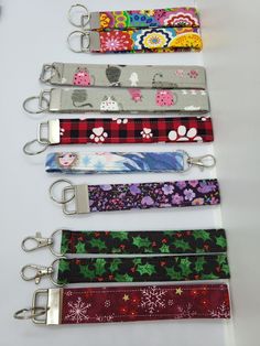 six lanyards are lined up on a white table with keychains attached to them