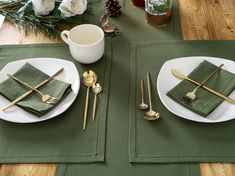 the place setting is set with green napkins and gold cutlery, along with silverware