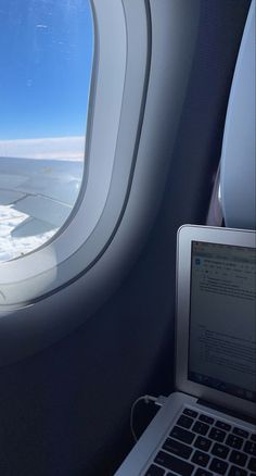 an airplane window looking out at the snow and ice in the distance, with a laptop on the desk