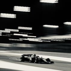 a black and white photo of a race car speeding down the track with motion blurry in the background