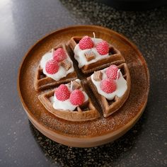 waffles topped with whipped cream and raspberries on a brown plate sitting on a table