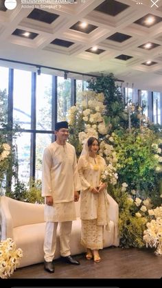 a man and woman standing next to each other in front of a floral display at a wedding