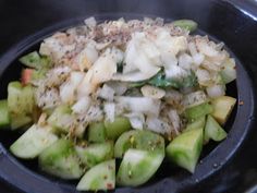 a black bowl filled with chopped vegetables on top of a stovetop burner and topped with seasoning