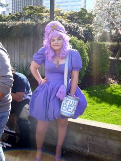 a woman dressed in purple is posing for the camera