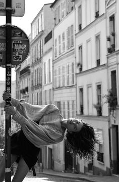 a woman leaning up against a street sign