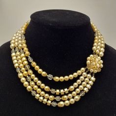 Step back in time with this beautiful 1950s vintage necklace. Features a cluster of pale yellow faux pearl beads that connects to multiple strands of clear glass beads, pale yellow faux pearl beads in different shapes and beautiful gold tone findings, complimenting each other very well. Easy to wear with a gold tone hook clasp. Treat yourself to this vintage gem or gift a loved one who adores vintage accessories, this necklace is sure to become a favorite in any vintage jewelry collection. Signed JAPAN. Circa 1950s/1960s. TO VIEW MORE FROM NEW VINTAGE FOR YOU, GO HERE: https://newvintageforyou.etsy.com All vintage items are sold as is in pictured condition. I do not alter or repair any vintage items because I feel it is important to maintain the authentic history of the piece. The photos a Multi Strand Beaded Necklace, Adored Vintage, Vintage Beads Necklace, Hook Clasp, Multi Strand Necklace, Jewelry Companies, 1950s Vintage, Pale Yellow, Strand Necklace