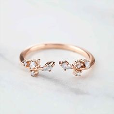 a rose shaped ring with three small white stones on the front and one diamond in the middle