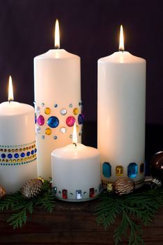 three white candles sitting next to each other on top of a wooden table covered in christmas decorations