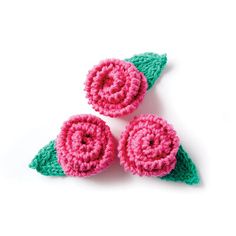 three crocheted pink and green flowers on top of each other