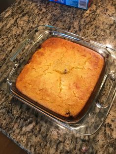 a cake in a glass baking dish on a granite counter top next to a box of milk