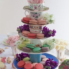 a three tiered cake stand filled with macaroons and flowers