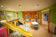 a child's playroom with slide, table and chairs in the room that is brightly colored