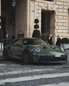 a green sports car parked in front of a building