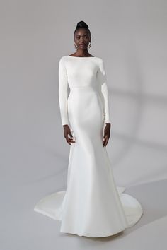 a woman in a white wedding dress standing on a white surface with her hands on her hips