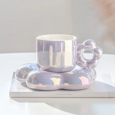 a coffee cup and saucer sitting on top of a white plate with silver decorations