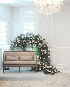 a couch sitting under a chandelier next to a flower covered arch in a living room