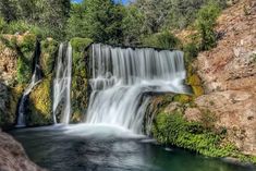 the waterfall is surrounded by lush green trees