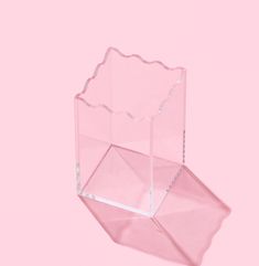 an empty pink vase sitting on top of a pink surface with the bottom half cut off