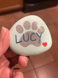 a person holding a rock with a paw on it that says lucky in blue ink