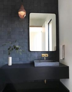 a bathroom sink with a mirror above it and a vase on the counter next to it