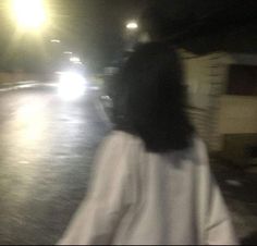 a blurry image of a woman walking down the street at night with her hand on her hip