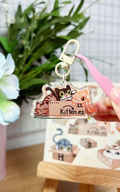 a person holding a keychain with an image of cats on it