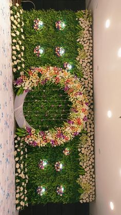 an overhead view of a green wall with flowers and lights in the center, surrounded by grass