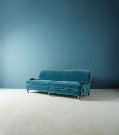 a blue couch sitting on top of a white floor next to a lamp and wall