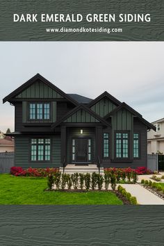 a house with dark green siding and flowers in the front yard