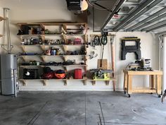 a garage filled with lots of tools and equipment on shelves next to a refrigerator freezer