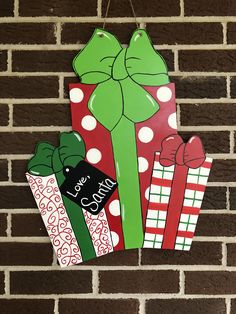 three christmas gift tags hanging on a brick wall with bows and presents attached to them