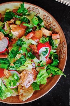 a salad with chicken, lettuce and tomatoes in a bowl on a table