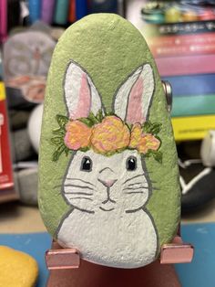 a painted rock with an image of a bunny wearing a flower crown on it's head