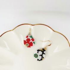 a pair of beaded earrings sitting on top of a white plate