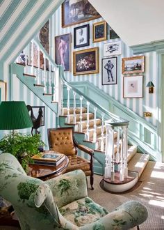 a living room filled with lots of furniture and pictures on the wall next to a stair case