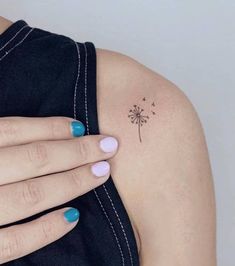 a woman's hand with a small tattoo on her left arm and a dandelion in the middle