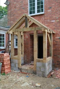 a house being built in front of a brick building with a wooden frame and door