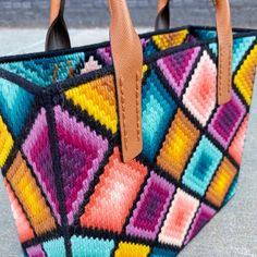 a multicolored handbag sitting on top of a sidewalk