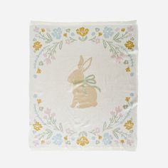 a napkin with a rabbit on it and flowers around the edges in pastel colors