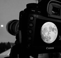 a black and white photo of a camera with the moon in the background