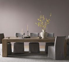 a dining room table with chairs and a vase filled with flowers on top of it