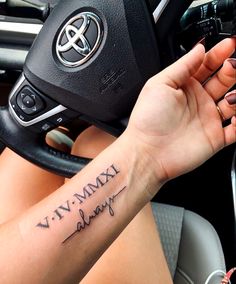 a woman driving a car with a tattoo on her arm that reads, viv vmxy bling